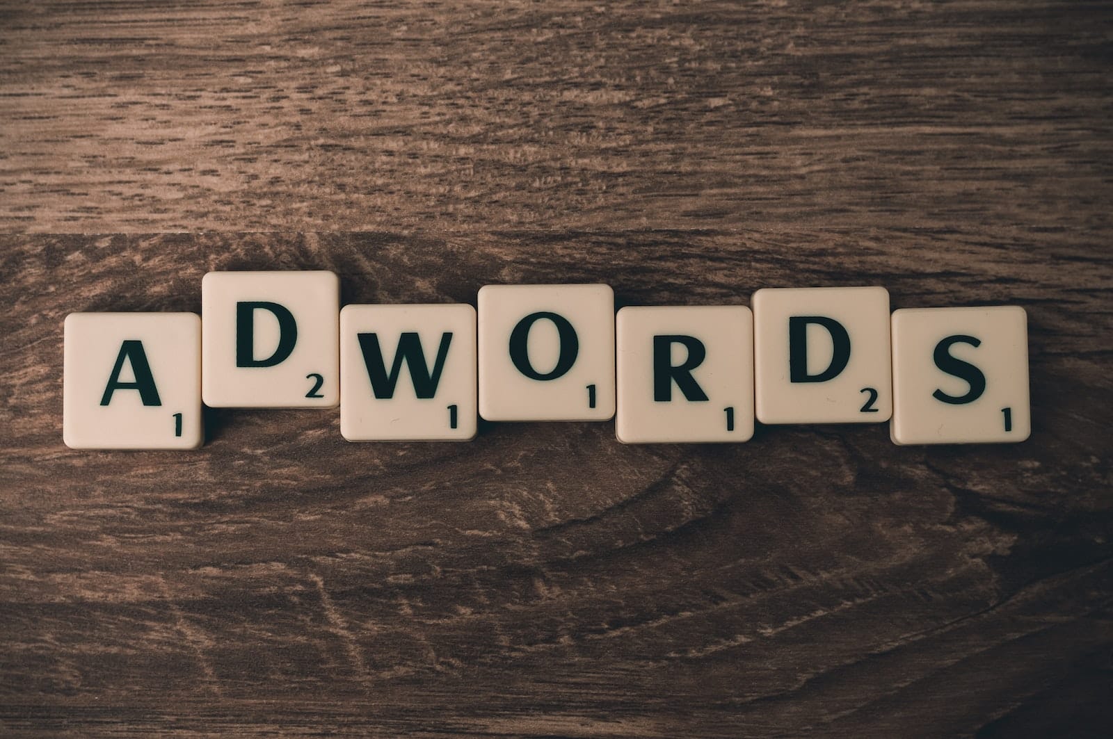 Scrabble Forming Adwords on Brown Wooden Surface